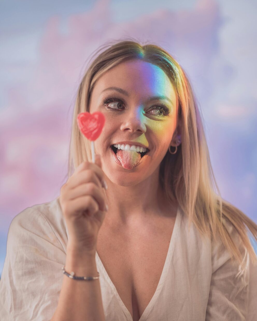 woman with teeth whitening from Greenwich Cosmetic Dentistry office making a silly face with a heart-shaped lollipop