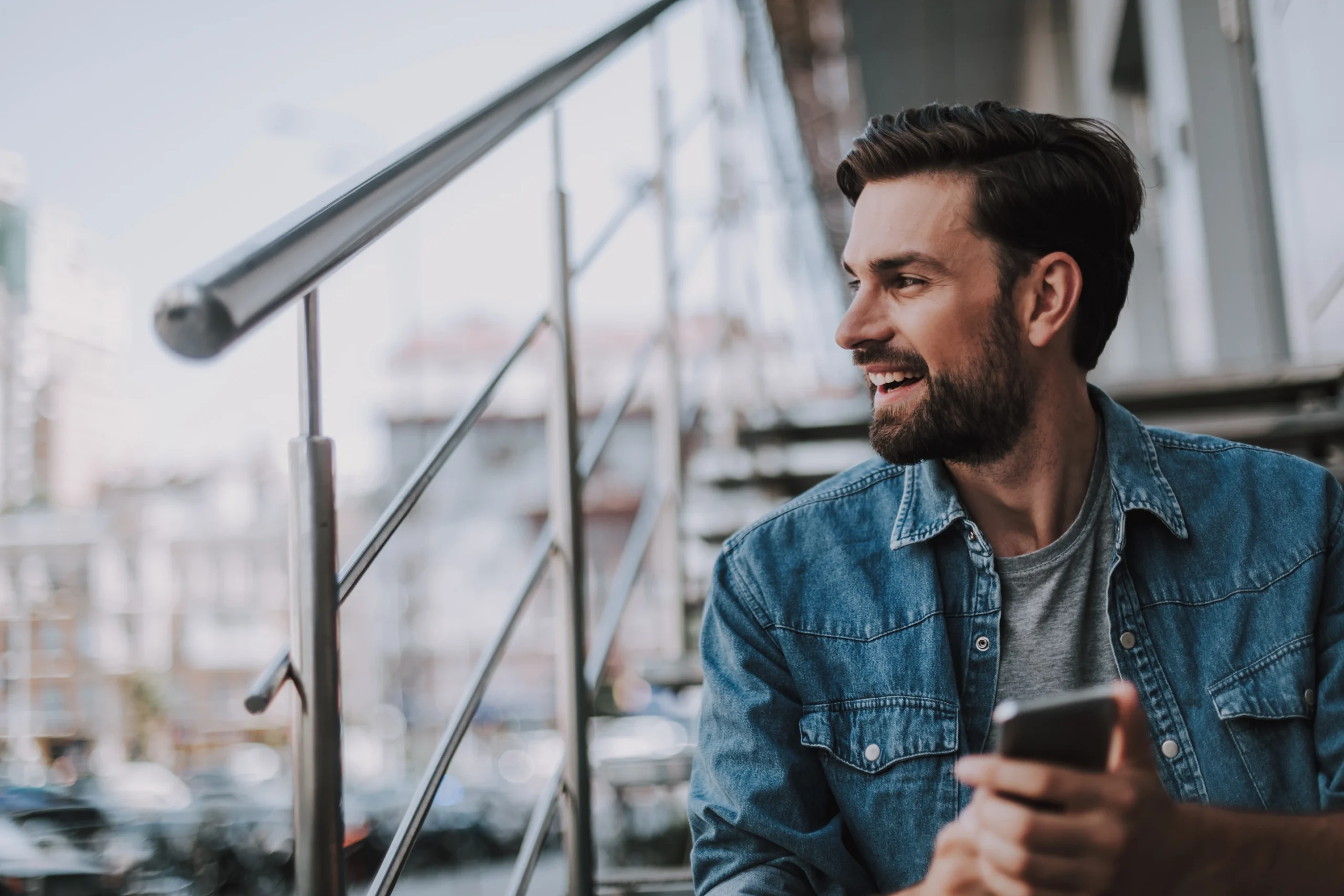 men sitting on the stairs looking outside holding a coffee